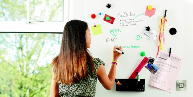 A young girl using British Gypsum ThistlePro Magnetic plaster to plan out her studies