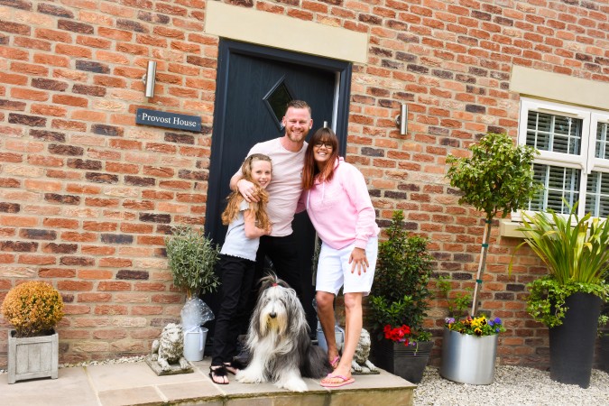 James in front of his self-build home with his family